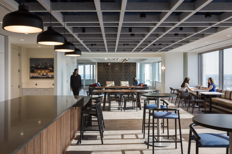 associates chatting in an open cafeteria/collaboration room with lots of tables.