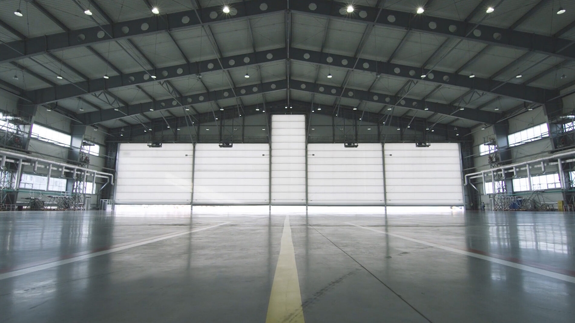 Roller shutter door and concrete floor inside factory building for industrial background. Airplane in front of half opened door to hangar. The open door of the hangar.