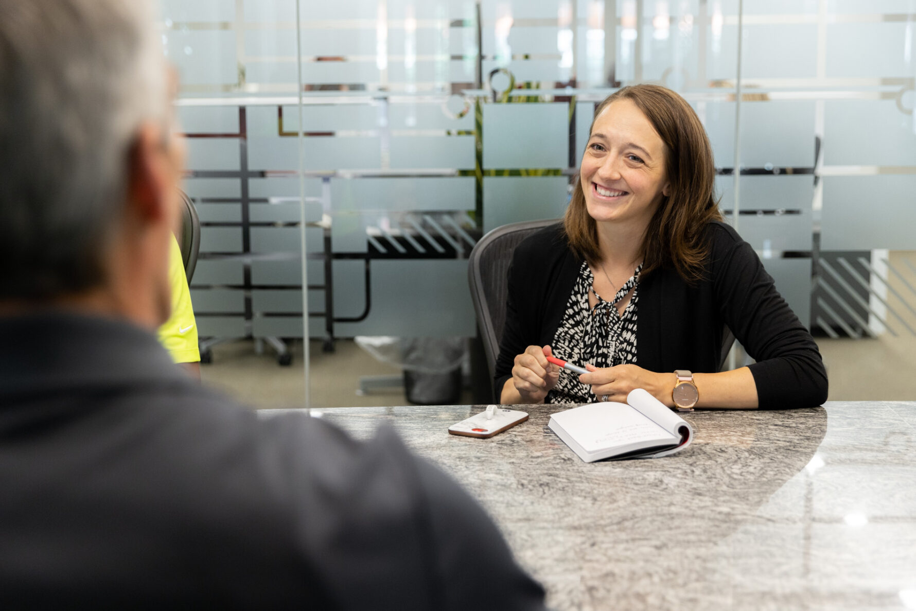 McCownGordon associate smiling and taking notes during a meeting.